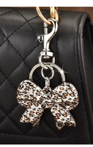 Detail of leopard print bow keychain with crystals on a black quilted leather bag