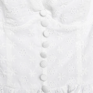 Close-up of white floral embroidery and cloth-covered buttons on an A-line dress
