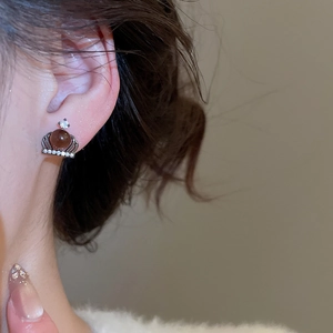 Detail of crown stud earring with dark brown gemstone and zircon on female ear