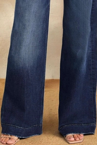 Detail view of dark blue wide-leg jeans featuring distressed wash and raw fringe hems