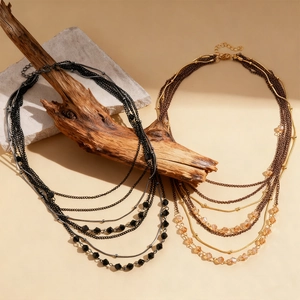 Detail of bohemian layered beaded necklaces featuring black and amber glass beads on rustic props