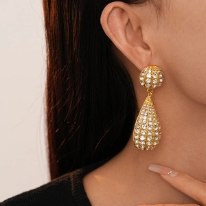 Macro view of a model wearing sparkling gold teardrop earrings with pavé rhinestones