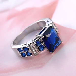 Macro shot of silver ring with large square blue gemstone and side zircon accents
