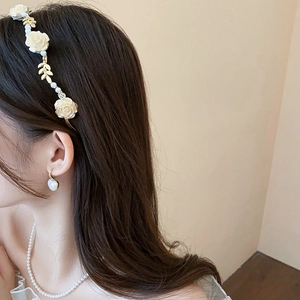 Détail du serre-tête fleuri doré avec perles blanches et boucles d'oreilles assorties