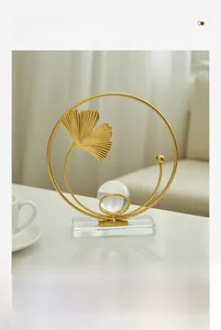 Detailed view of golden ginkgo leaf ornament with glass sphere on transparent base