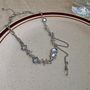 Detail of silver cat-eye necklace with thorn links and blue stones on porcelain