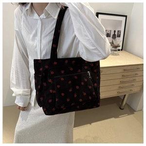 Detail of strawberry pattern corduroy tote bag featuring a front zipper pocket and soft texture