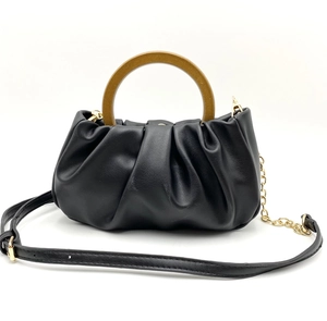 Detail of black pleated cloud bag featuring a round wood-grain handle and sleek PU leather