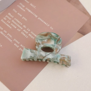 Macro detail of marble pattern hair claw clip with green and orange tones