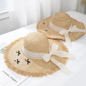 Chic beige raffia sun hats with ribbon bow and pearl detail in a flat lay view