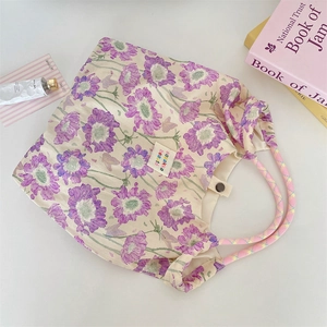 Close-up of floral tote bag with woven handles, interior snap button and brand label