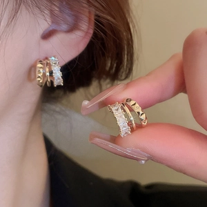 Gold C-shaped stacked earrings with sparkling zircon stones and pyramid stud texture
