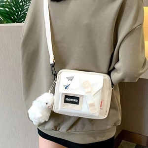 White canvas crossbody bag with airplane pins and a cute plush bunny charm