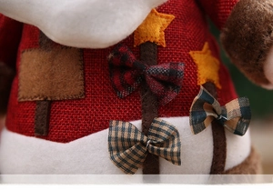 Close-up of linen Christmas plush doll featuring star patch and plaid bow detail