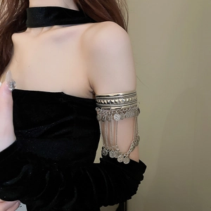 Detail of silver arm cuff with coin charms and metal tassels in bohemian style