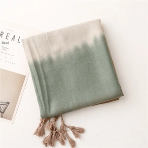 Detail of gradient bean green scarf with long woven tassels on minimalist magazine