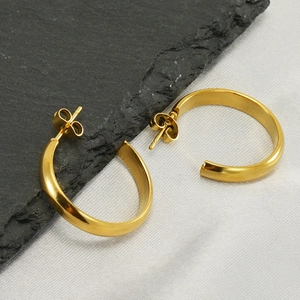 Polished golden C-shape stainless steel hoop earrings on elegant silk background