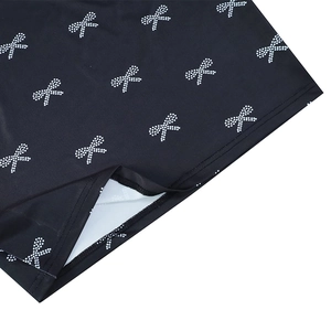 Detailed view of black fabric featuring white dot bow print and clean hem stitching