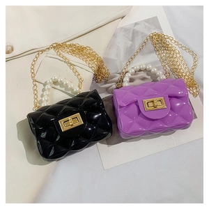 Detail of glossy jelly bags with pearl handles and golden chain straps in quilted design