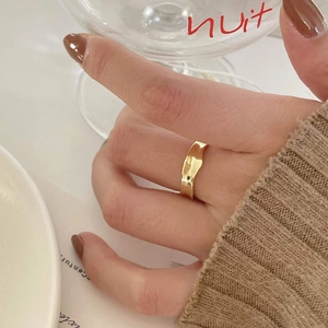 Close-up of minimalist irregular gold wave ring on finger with elegant aesthetic style