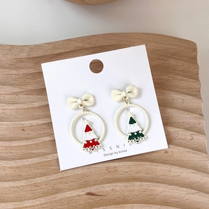 Detail of Christmas tree earrings with cream bows on a wooden display background