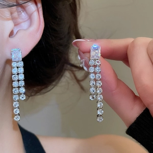 Macro view of long silver tassel earrings with rectangular cubic zirconia crystals