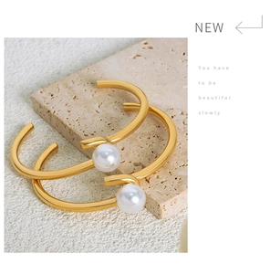 Detail of minimalist gold-plated titanium bangles with large white pearls on stone