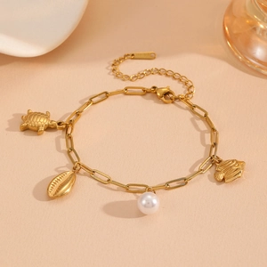 Detail of gold turtle, seashell and fish charms bracelet with a lustrous white pearl