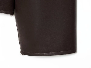 Macro detail of dark brown faux leather texture and premium stitching on reversible jacket