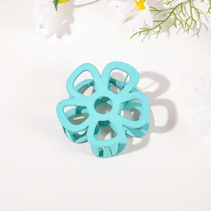 Macro shot of mint green flower hair claw clip with matte finish and silver spring detail