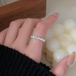 Close-up of textured 925 sterling silver heart ring with wave pattern on hand
