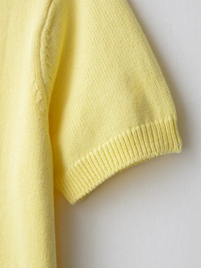 Macro detail of high-quality yellow knit cardigan fabric with elastic ribbed cuff
