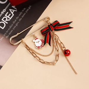 Festive Christmas brooch with Santa pendant, red bow, and bell on a gold pin
