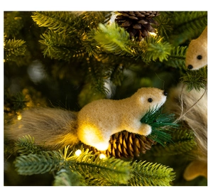 Detail of a fuzzy squirrel ornament with a long furry tail hanging on a Christmas tree