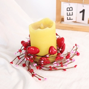 Detail of red heart berry candle ring with a yellow pillar candle on white fabric