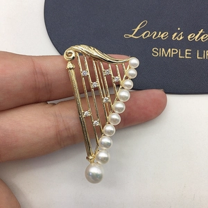 Macro detail of harp-shaped gold brooch with freshwater pearls and sparkling crystals