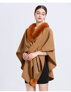 Detail of camel wool poncho featuring faux fur collar and decorative hanging pom-poms