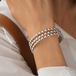Dettaglio di un bracciale argento a tre strati con sfere metalliche lucide e consistenza