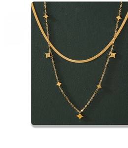 Detailansicht einer goldenen Doppelkette mit Sternen auf grünem strukturiertem Grund