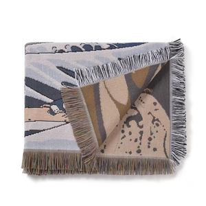 Detail of woven bohemian blanket showing colorful tassels and jacquard texture