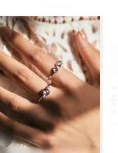 Détail de bagues en argent avec zircone violette facettée sur main et dentelle blanche