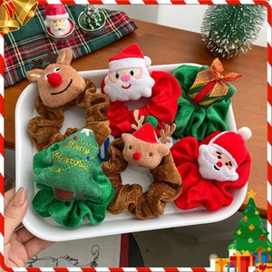 Close-up of festive Christmas scrunchies with plush Santa, reindeer, and tree charms
