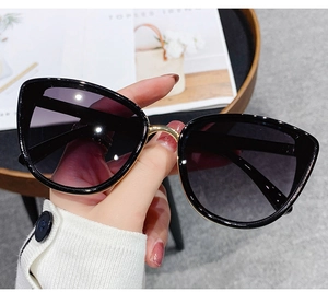 Detailed view of oversized butterfly sunglasses with black lenses and gold metal bridge
