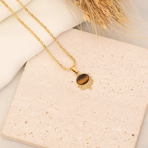 Gold stainless steel beaded necklace featuring an oval tiger eye stone pendant and grain detail