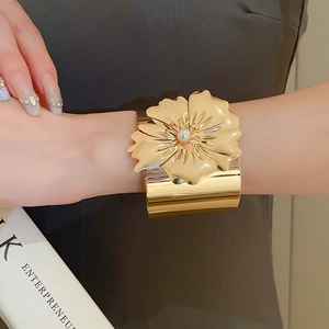 Macro shot of gold floral cuff bracelet featuring a centered white pearl and petal textures