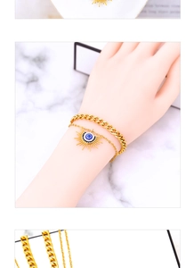 Gros plan du bracelet doré multicouche avec chaîne gourmette et pendentif œil protecteur