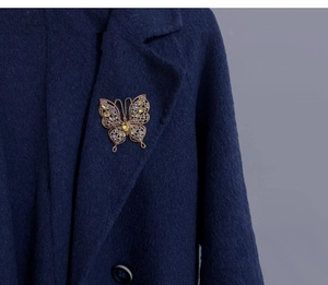 Détail d'une broche papillon vintage avec cristaux colorés sur un manteau en laine