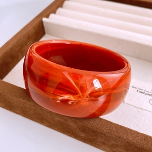 Vue détaillée du bracelet en acrylique orange marbré avec une texture fumée lisse