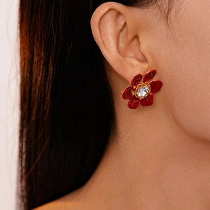 Close-up of vintage red enamel flower earring with central sparkling crystal on model ear