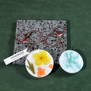 Détail de pendentifs ronds en résine avec fleurs séchées et porte-clés en argent